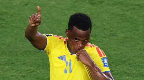 A Colombia fan kisses a fake World Cup trophy
