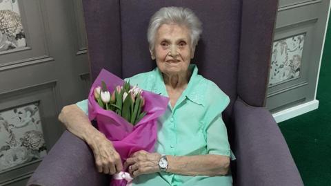 Lilian Ross sitting down holding a bunch of tulips