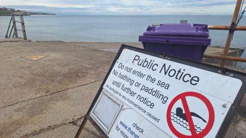 A sign advising people not to enter the sea. It says no bathing or paddling until further notice.