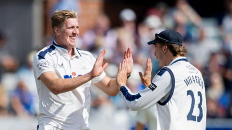 Will Sutherland high-fives James Wharton (right) after taking a wicket