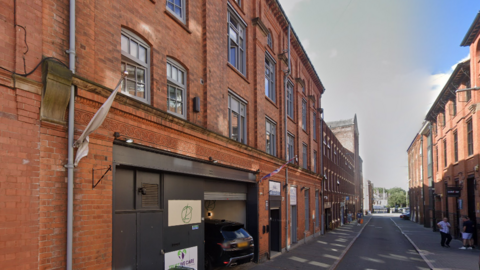 A streetview image of a narrow street surrounded by buildings with at least three floors 