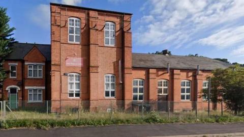 The ex-military base in Camberley, it is a red concrete building with a fence. 