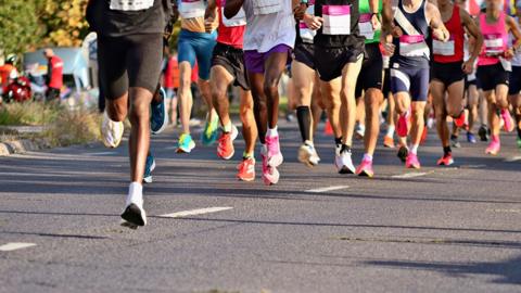 A generic picture showing the legs of marathon racers running along a road