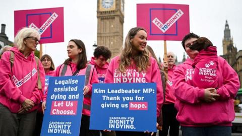 Campaigners in favour of legalising assisted dying hold placards at a rally outside the Houses of Parliament 