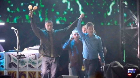 Liam and Noel Gallagher on stage, holding hands in the air.