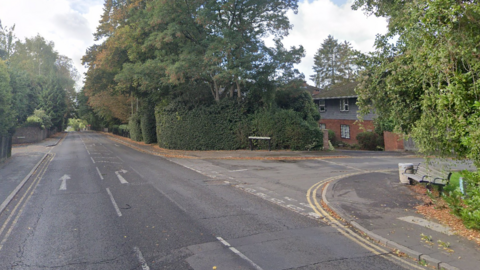 An empty road junction, with greenery either side and a house on the right-hand side