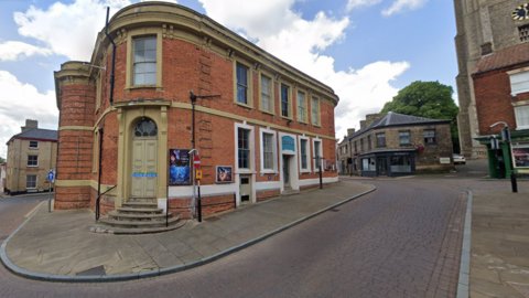 The outside of Central Cinema Fakenham, a red brick, double-storey building on a paved street. 