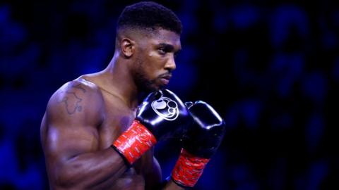 Anthony Joshua stands with his gloves up in the ring