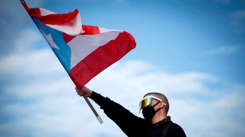 A protester waves a Puerto Rican flag