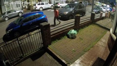 Man walking past cars on an evening in Cardiff