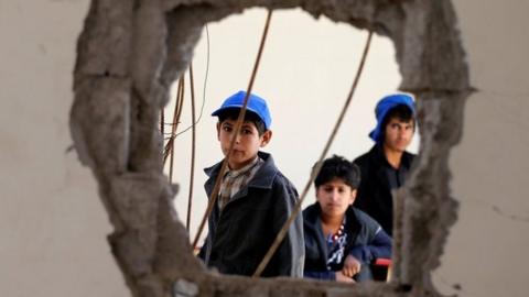 Boys look through a hole in a wall in their school in Sanaa, Yemen, reportedly caused by a Saudi-led coalition air strike (5 October 2016)