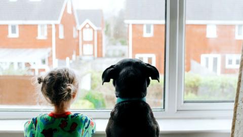 Little girl looks out window to empty street