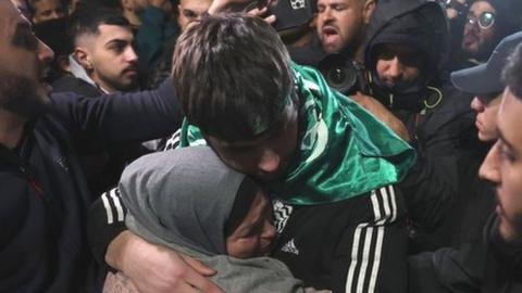 A Palestinian teen hugs a family member after being released