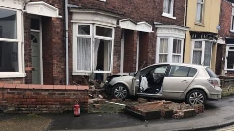 Car crashed into front of a house with wall rubble surrounding the vehicle