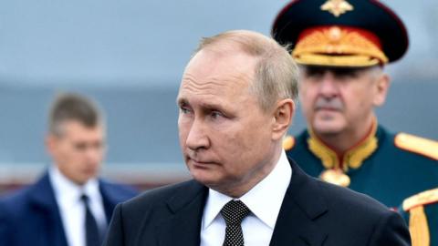 Russia's President Vladimir Putin (L), flanked by Russia's Defence Minister Sergei Shoigu (R), walks as he takes part in the main naval parade marking the Russian Navy Day, in St. Petersburg on July 31, 2022.