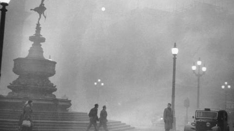 Pedestrians struggle to see through the dense fog in Piccadilly