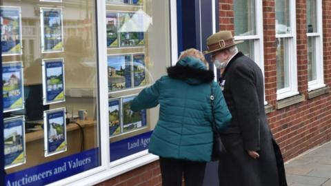 Couple looking at housing in estate agent in masks