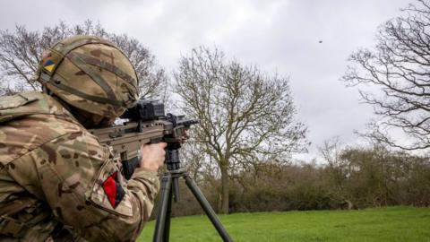 A soldier takes aim at a drone