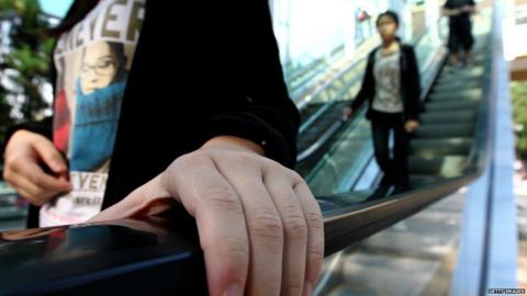 person holds escalator handrail