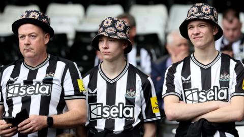 Three men wearing Newcastle United shirts