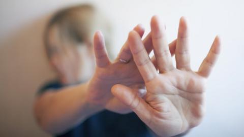 Woman stretches out arms to protect herself