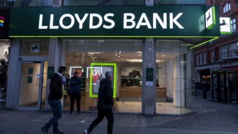 People walk past Lloyds bank branch