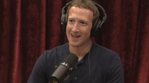 Mark Zuckerberg wears headphones and sits in front of a microphone