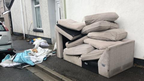 Flood-damaged sofa on pavement