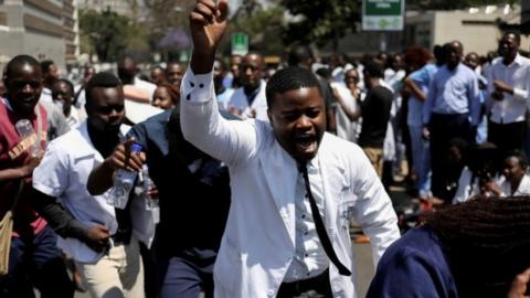 Doctors sing and hold placards during a protest over the disappearance of the leader of their union in Harare, Zimbabwe