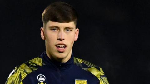 Oxford United defender Stephan Negru warms up for a League One game.