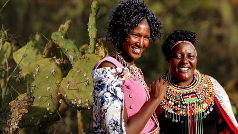 Two Twala women in traditional costumes and a cactus