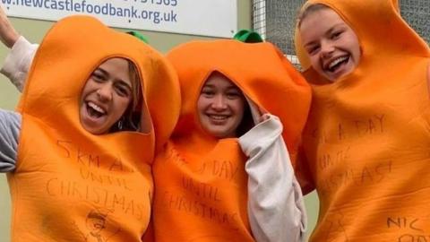 Three students are spending months running in carrot costumes to raise cash for a food bank.