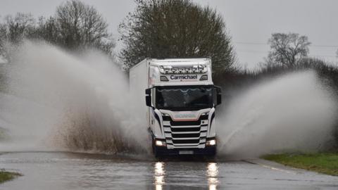 Lorry drives through flooded road