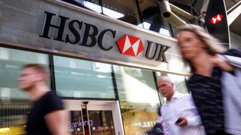 Pedestrians walk past a HSBC UK bank branch