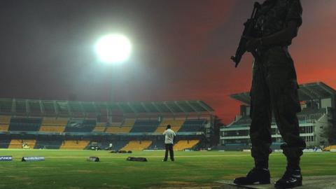 A soldier stands guard inside a cricket stadium