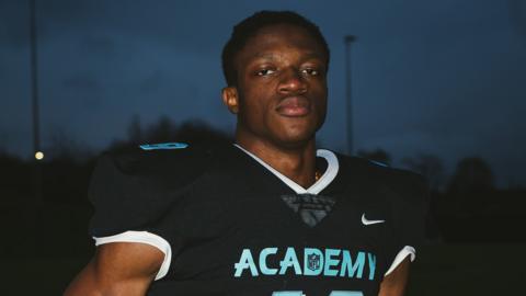 Emmanuel Okoye poses for a picture in NFL Academy gear