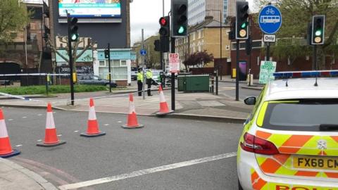 Image showing a police car parked in front of a cordon and traffic cones near the scene of the stabbing.