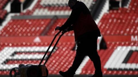 Ground staff at Old Trafford work to prepare the pitch