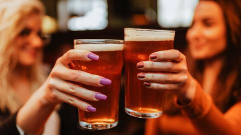 Stock photo of two women holding up pints
