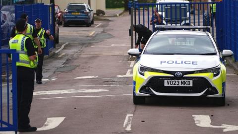 A police car and officers on foot at at school gates