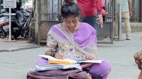 17-year-old Asma studies on a foothpath in India's Mumbai city.