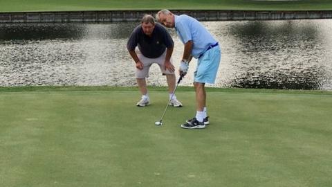 John Eakin putting on the 17th green at Sawgrass in a practice round with his guide Steve Killick lining up the shot