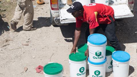 A handout picture provided on 09 October 2016 by Oxfam International shows members of an emergencies team of Oxfam delivering hygiene kits on 8th October 2016, to prevent the spread of Cholera and other diseases in the town of Camp Perrin, department Sud, Haiti