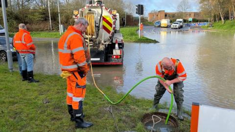 Men in orange hi-vis jackets working on the flood water