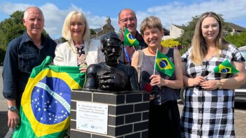 A sculpture of Donohoe with people standing around it holding Brazilian flags