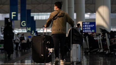A man wheels suitcases through an airport