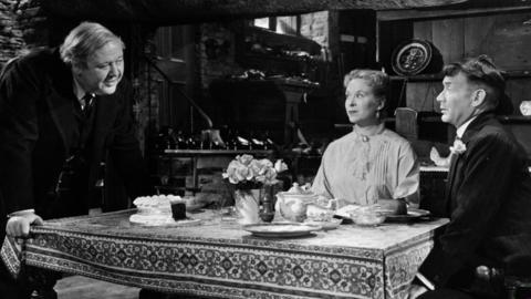 Charles Laughton stands over a table talking to Brenda DeBanzie and John Mill in a scene from the film 'Hobson's Choice', 1954