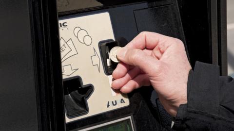 View of person putting coin into car parking machine