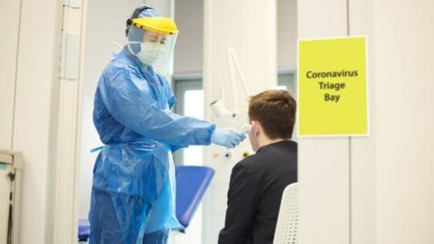 A nurse tests a person for coronavirus