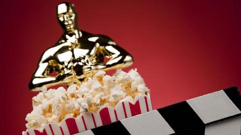An Oscar statue with popcorn and a clapperboard